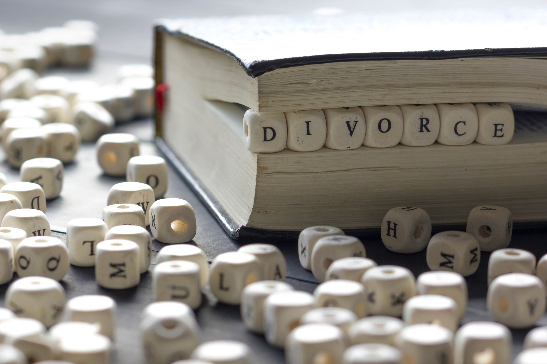 Divorce made up of wooden letters on the table with wedding rings.
